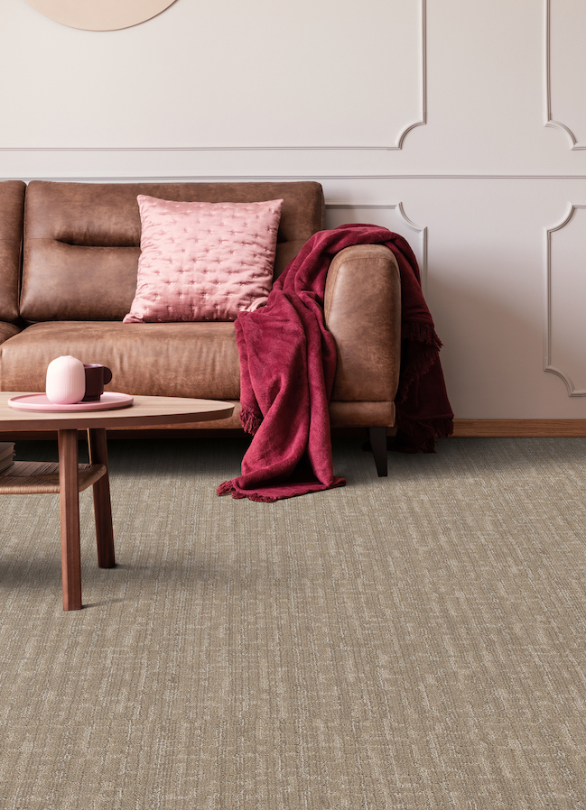 textured brown carpets in a stylish living room with brown leather couch and pink accents